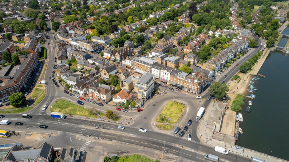 A wide view of a small town street in New Addington with a one-way traffic sign and a roundabout sign on the left, and a temporary barrier with a blue arrow on a red and white striped road marking in 